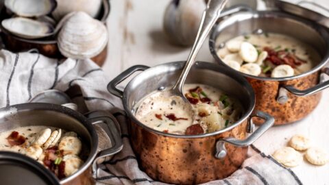 new england clam chowder in small copper pots with spoon and oyster crackers
