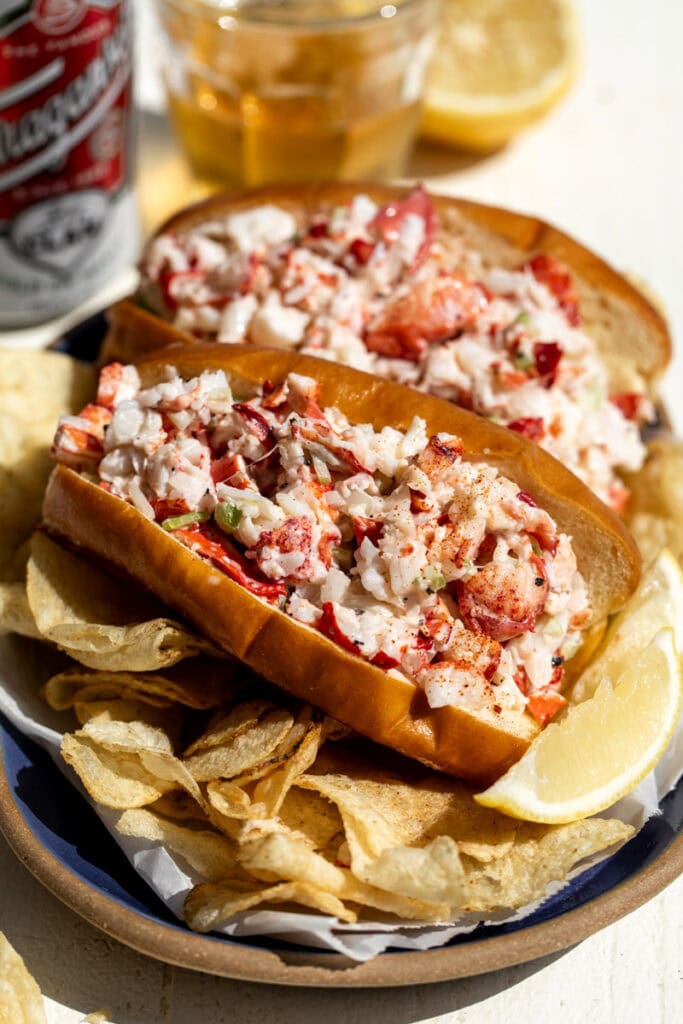 new england style lobster rolls in brioche buns with chips and lemon wedges.