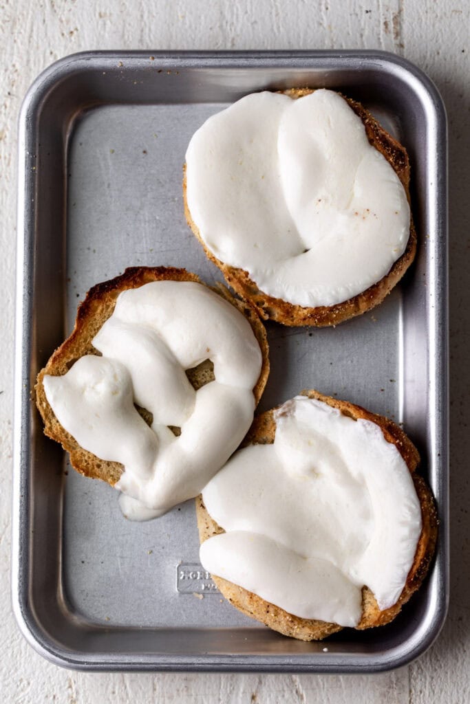 fresh mozzarella slices on english muffin toasted on baking sheet.