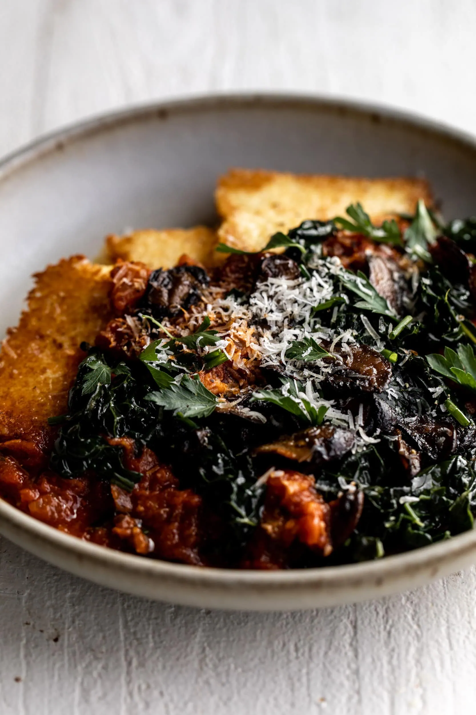 Crispy Polenta with Spicy Tomato Sauce, Sautéed Kale & Mushrooms with freshly grated parmesan cheese