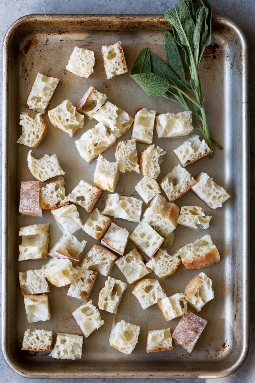 Dried out ciabatta bread pieces on a baking sheet.