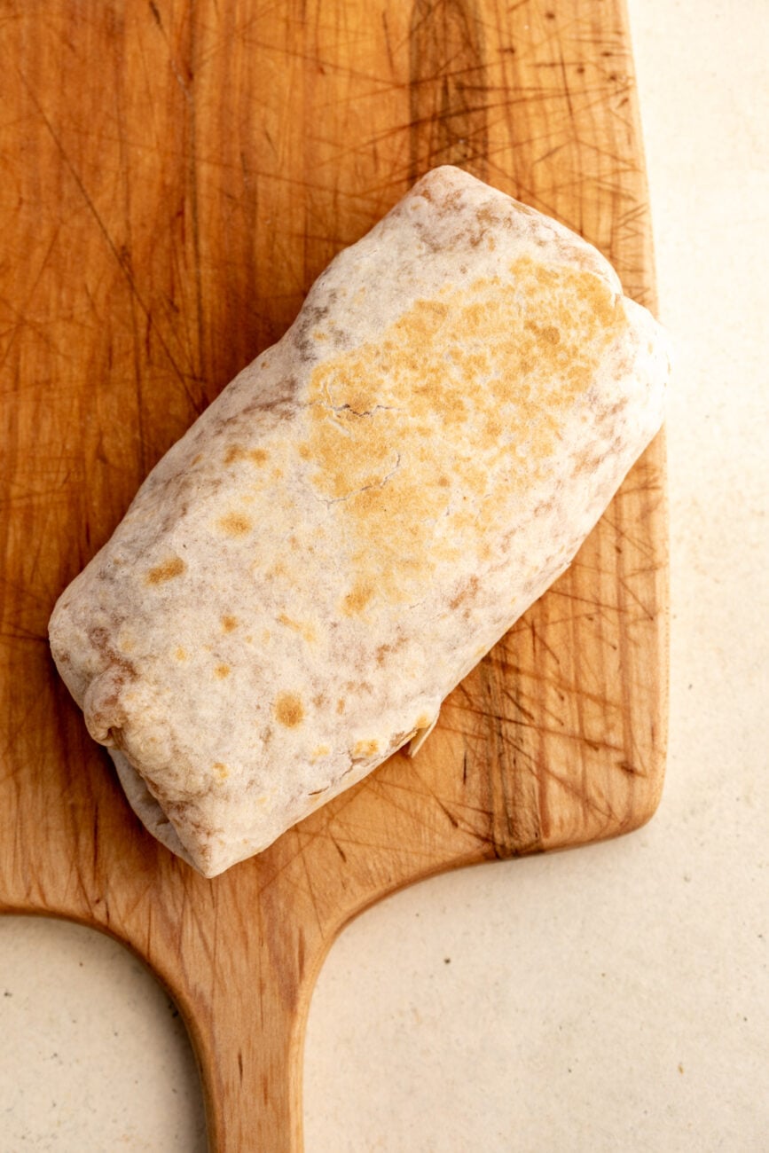 vegetarian breakfast burrito on cutting board.