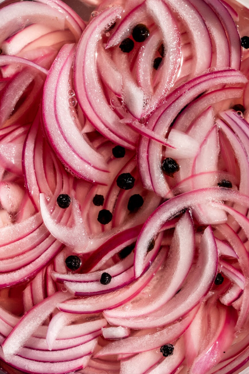 sliced pickled onions in brine with black peppercorns.