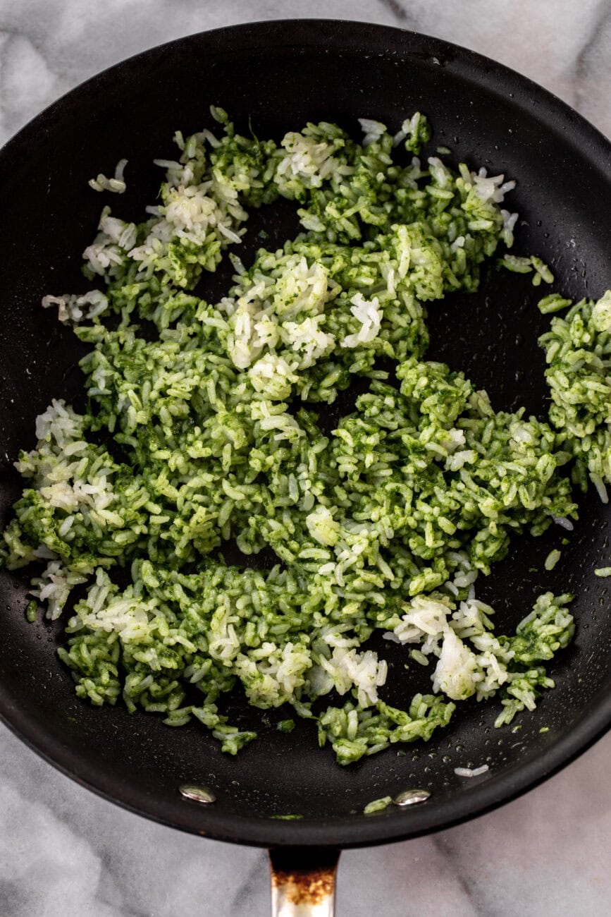 green sauce added to crispy rice in pan.