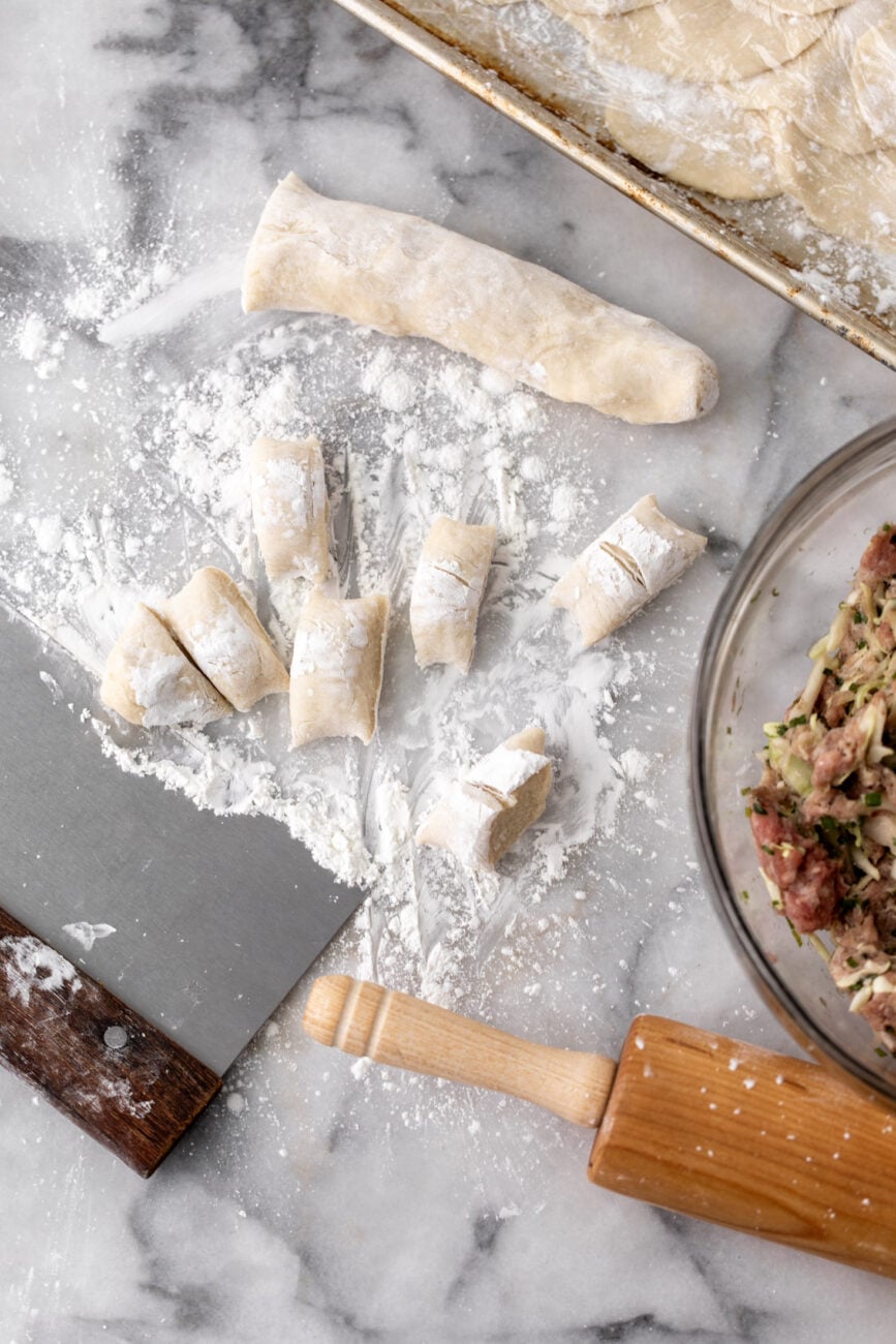homemade dumpling wrappers portioned out with rolling pin and filling. 