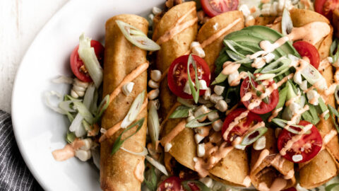 rolled taquitos in corn tortillas filled with potato, cheese and chorizo on a white plate