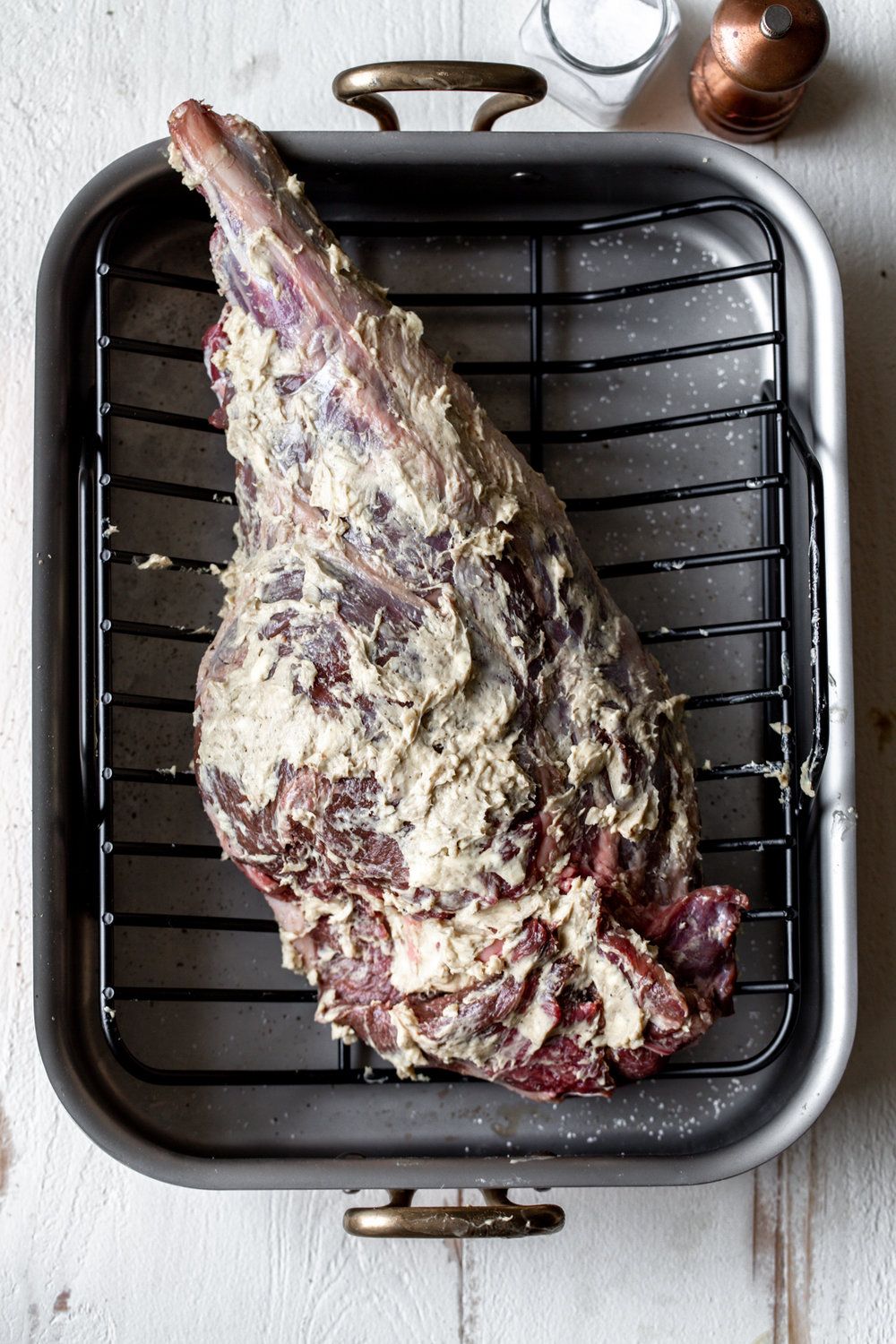whole leg of lamb rubbed in anchovy garlic butter in roasting pan