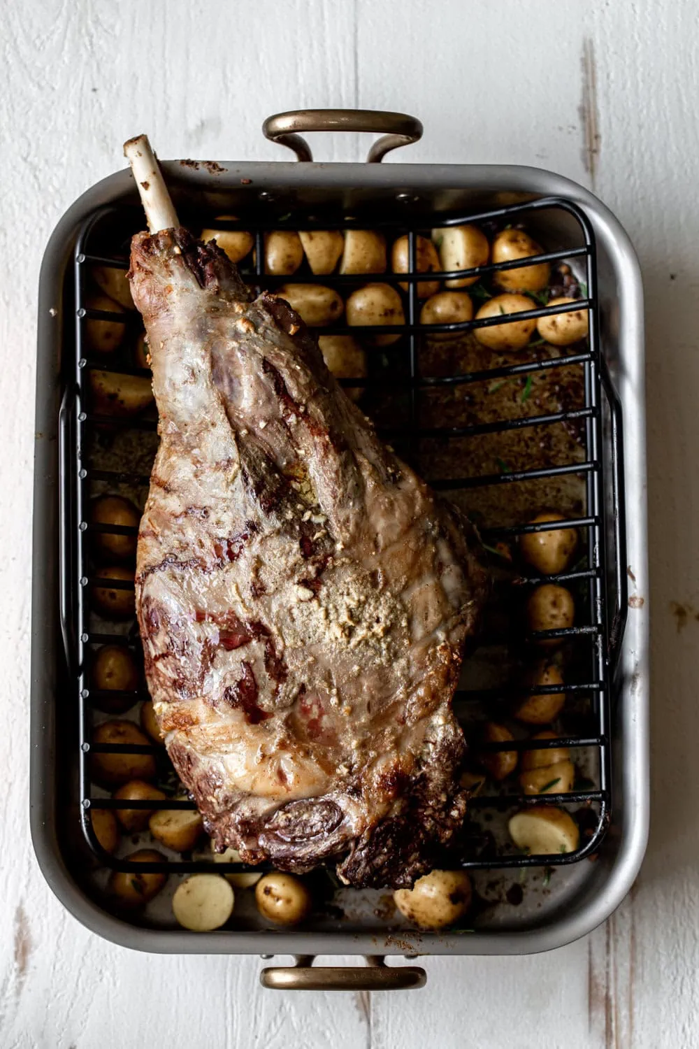 Anchovy-Garlic Butter Rubbed Whole Roasted Lamb Leg with Potatoes in roasting dish