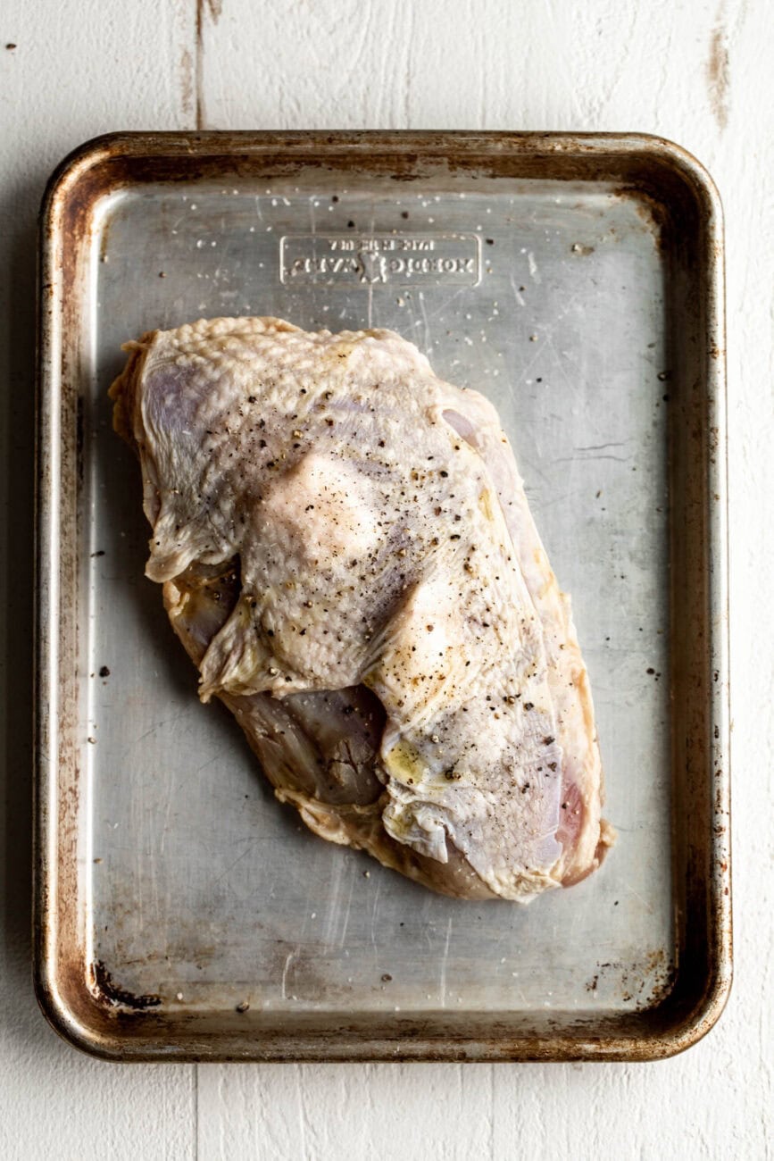 brined turkey breast on baking sheet with butter.