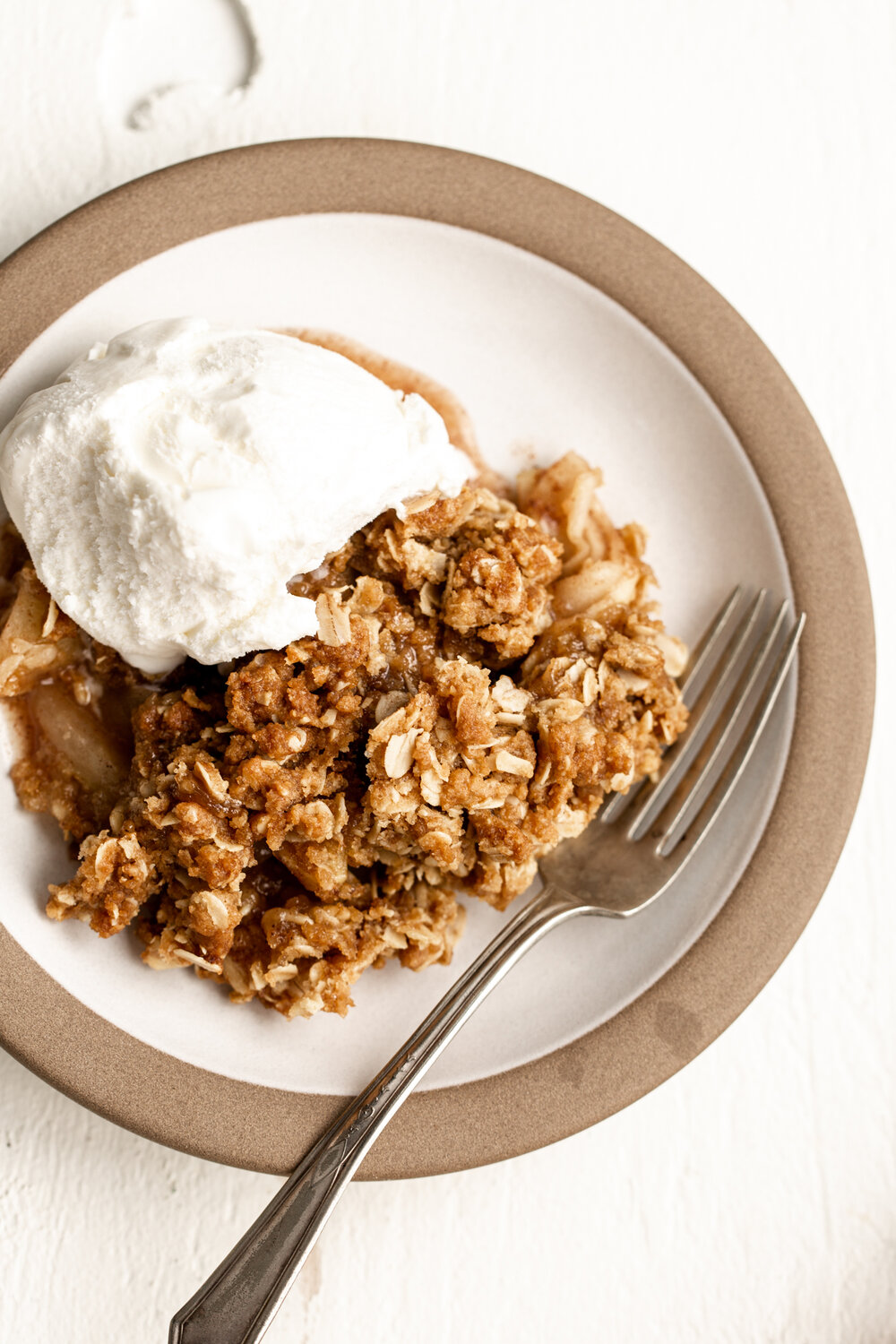 scoop of apple crisp fall dessert on a small plate with oat mixture topped with vanilla ice cream