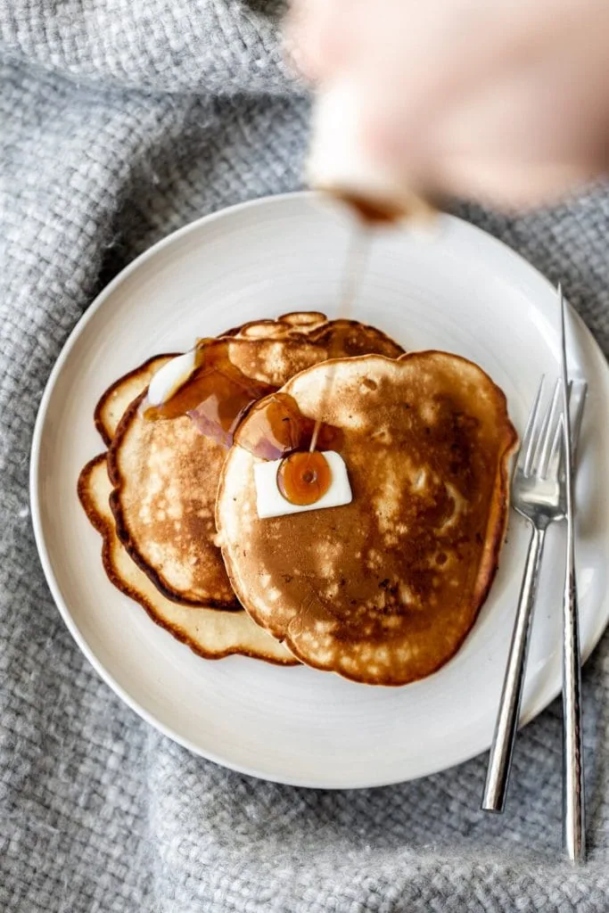 apple pancakes topped with butter and drizzled with maple syrup.