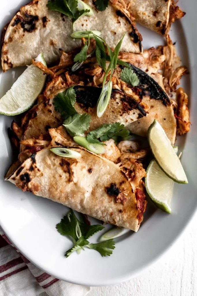 Baked Crispy Chicken Tinga Tacos with lime wedges.