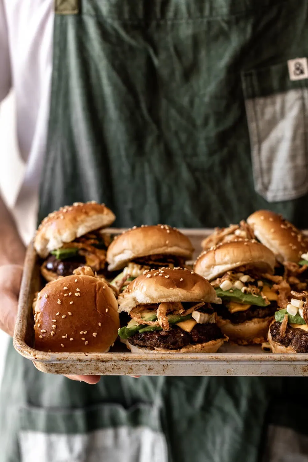 Beef Sliders with chipotle mayo and crispy onion strings on baking sheet
