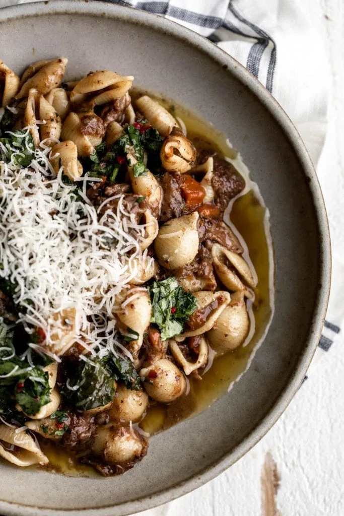 Braised Oxtail Ragu with Chile Gremolata recipe topped with parmesan cheese.