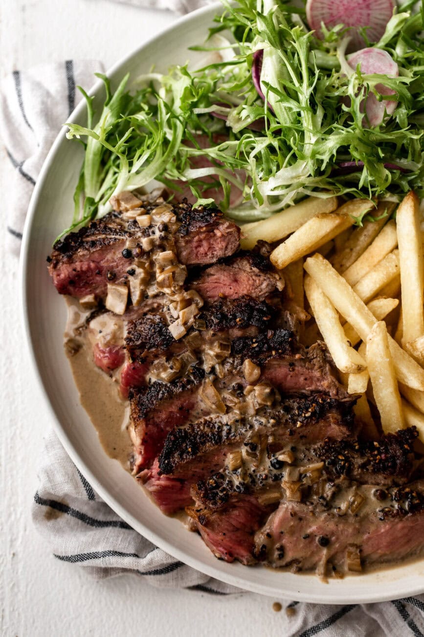 Butter-Basted Steak Au Poivre with Brandy Pan Sauce and french fries.