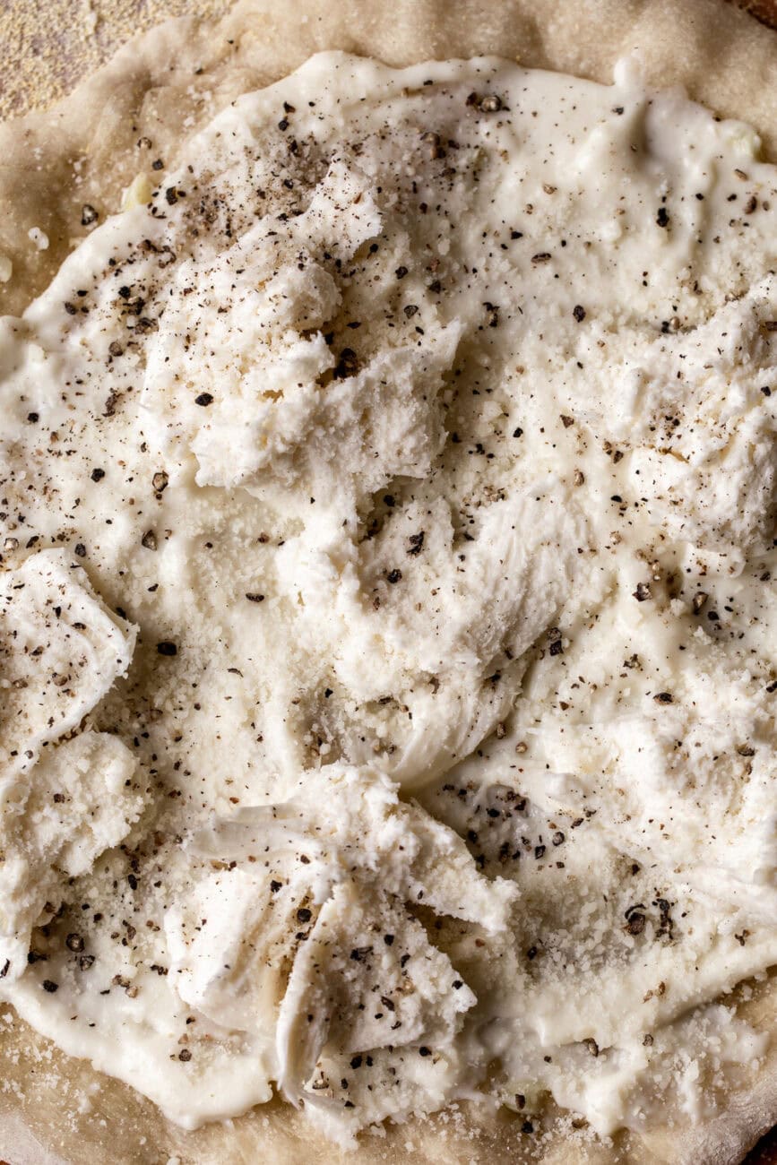 cacio e pepe pizza with cheese and black pepper assembled.