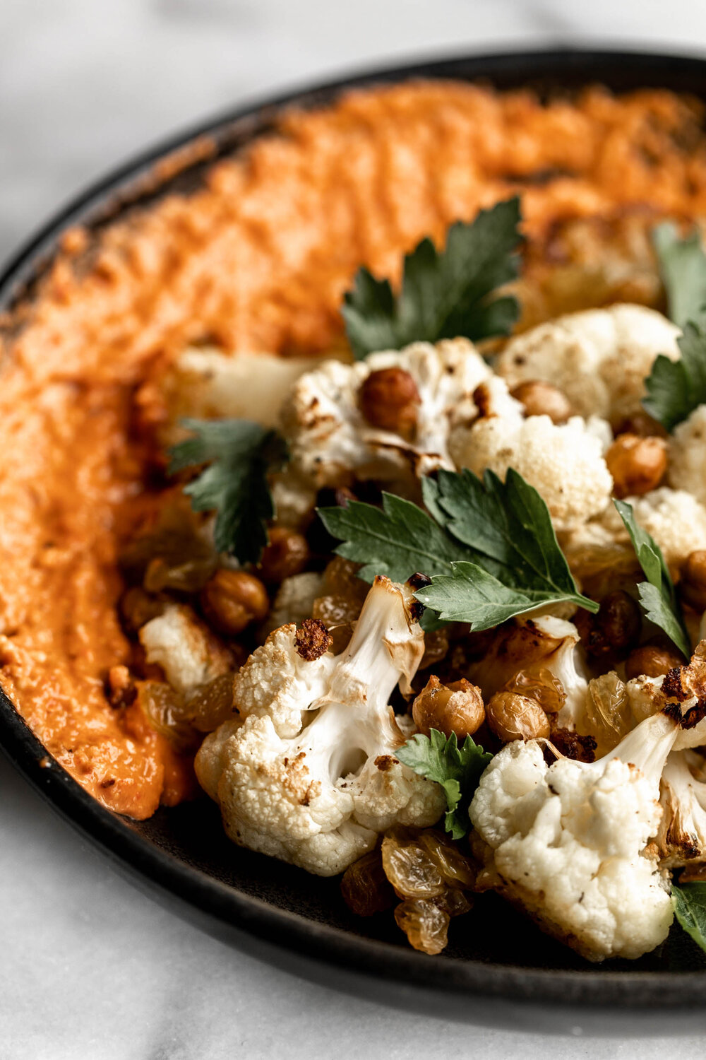 Charred Cauliflower with romesco and crispy chickpeas garnished with parsley