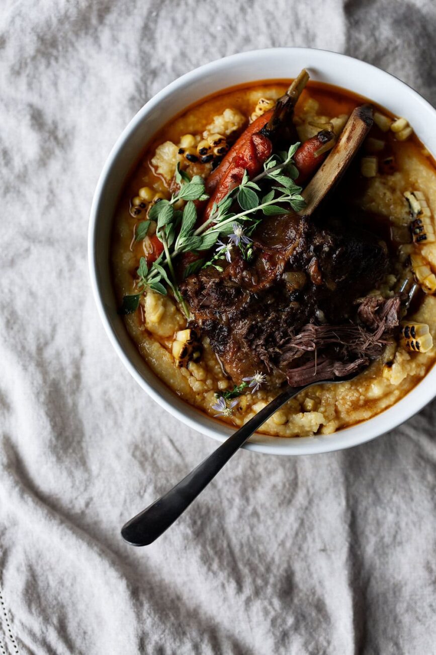Citrus Chili Braised Short Ribs with Carrots and Charred Corn Polenta in bowl with fork.