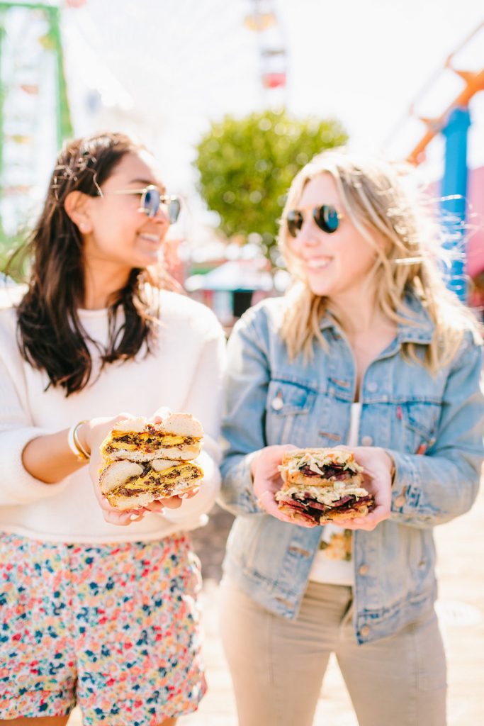 two women showing sandwich for the best day in Westside of Los Angeles