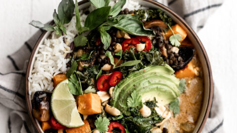 Coconut curry roasted sweet potato lentil bowl topped with avocado and lime wedge.