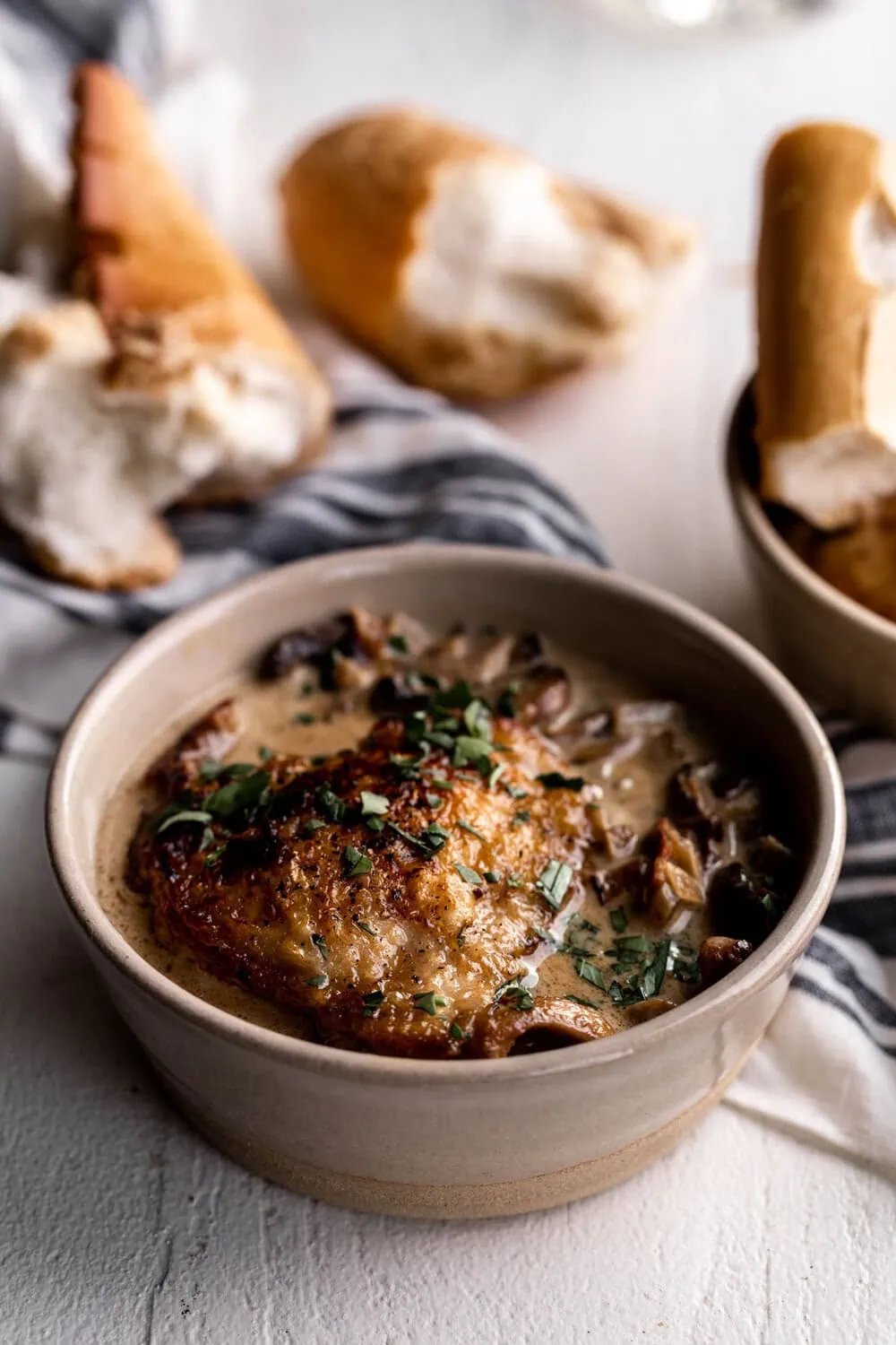 Coq Au Vin Blanc with mushrooms and bacon in a creamy white wine sauce with bread in bowls 
