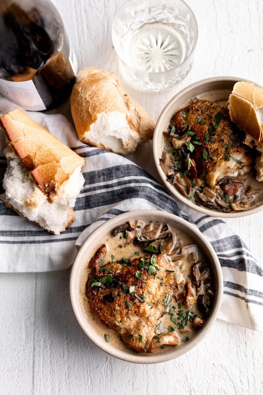 Coq Au Vin Blanc with mushrooms and bacon in a creamy white wine sauce with bread and white wine.