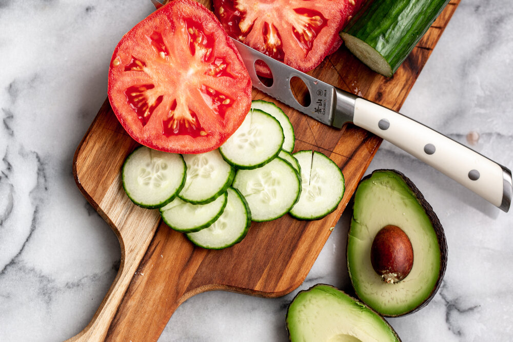 sliced cucumber and tomato with halved avocado