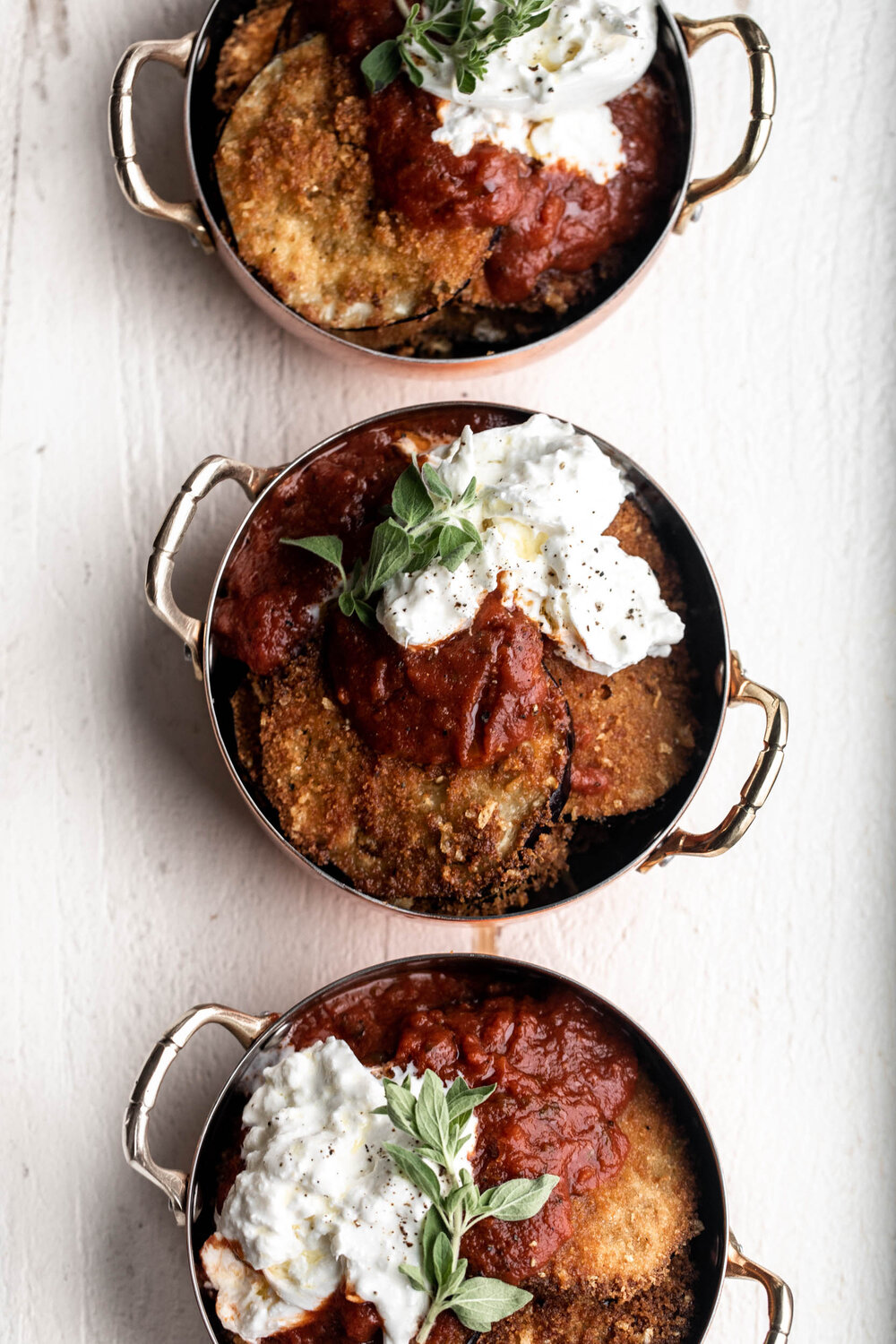 Eggplant parmesan individual serving dishes with tomato sauce and burrata