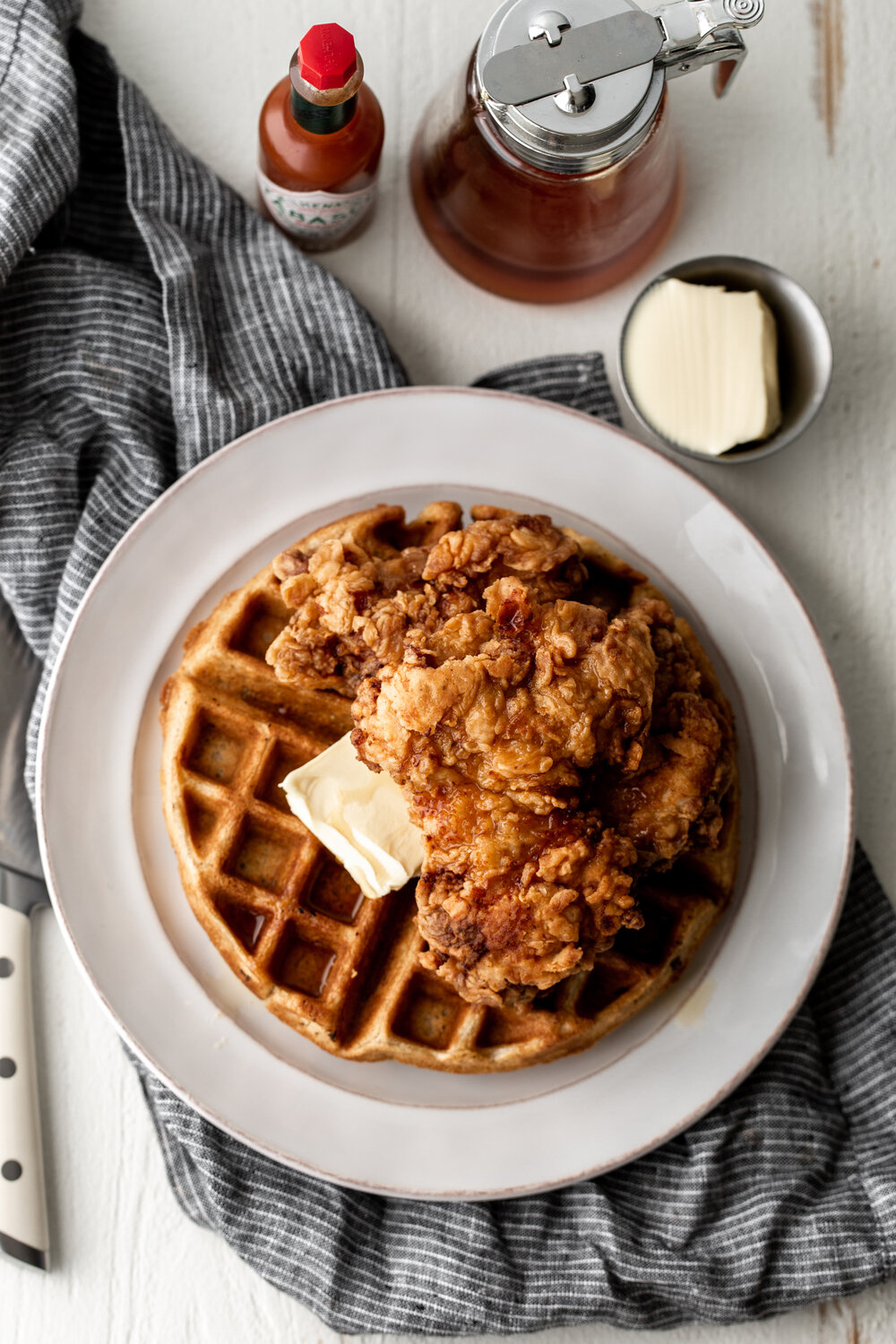 Fried chicken and waffles sweetened with a hint of cinnamon and served with hot sauce maple syrup is the ultimate sweet and savory meal