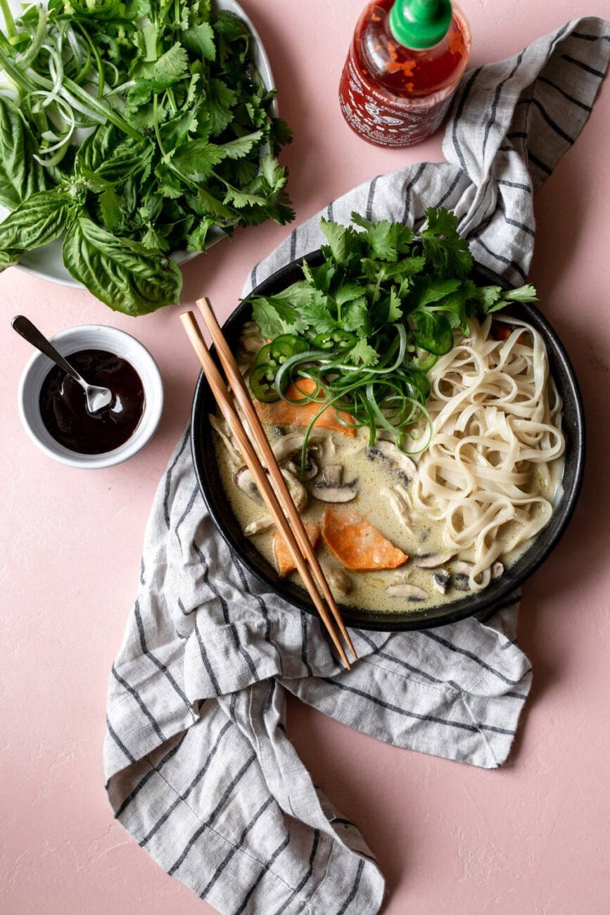 Green Curry Pho with Chicken with rice noodles garnished with herbs.