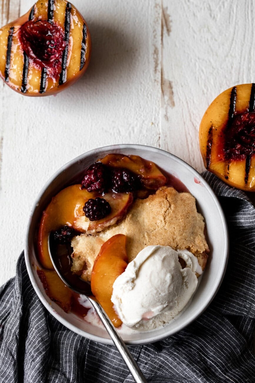 Grilled Peach and Blackberry Cobbler in bowl with vanilla ice cream.
