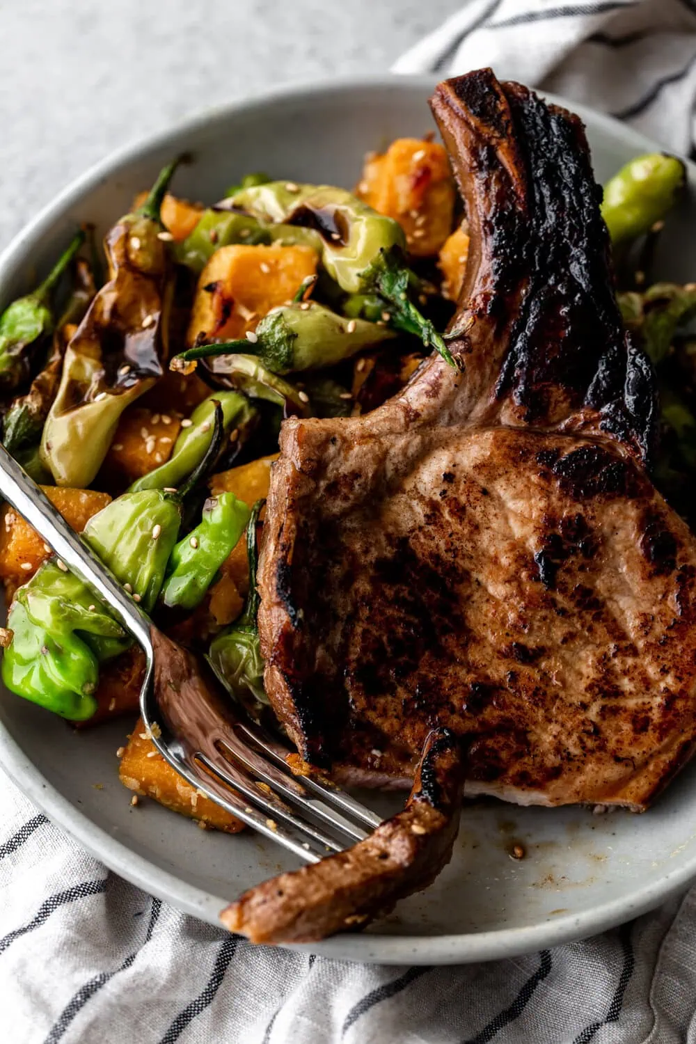 Pork chops marinated in honey-soy pan-seared served with miso roasted kabocha squash and shishito peppers 