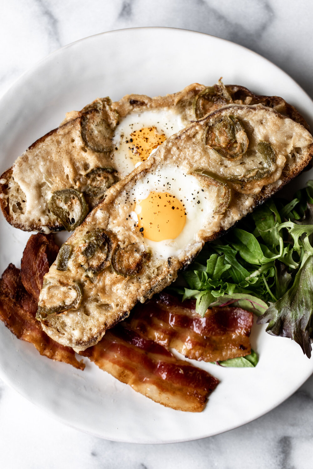 Classic egg in a hole toast gets and upgrade with a Parmesan and pickled jalapeño crust in this easy breakfast recipe. 