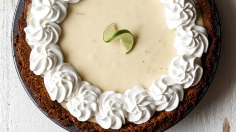 key lime pie with piped whipped cream and graham cracker crust.