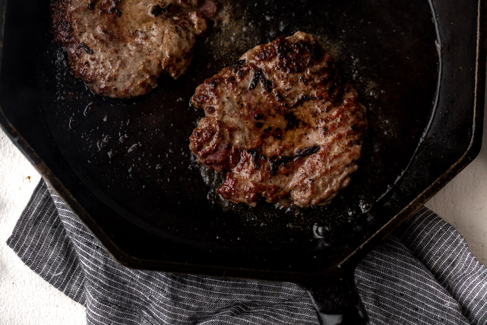 cooked burgers in cast iron skillet