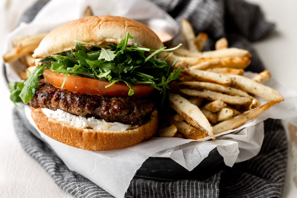 lamb burger with tomato arugula and aioli on a bun with fries