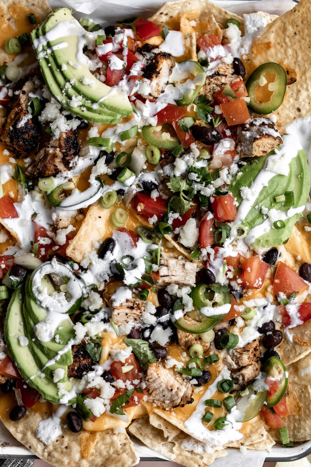 Loaded Three-Cheese Chicken Nachos with nacho cheese melted cheddar cotija with avocado, black beans and chicken