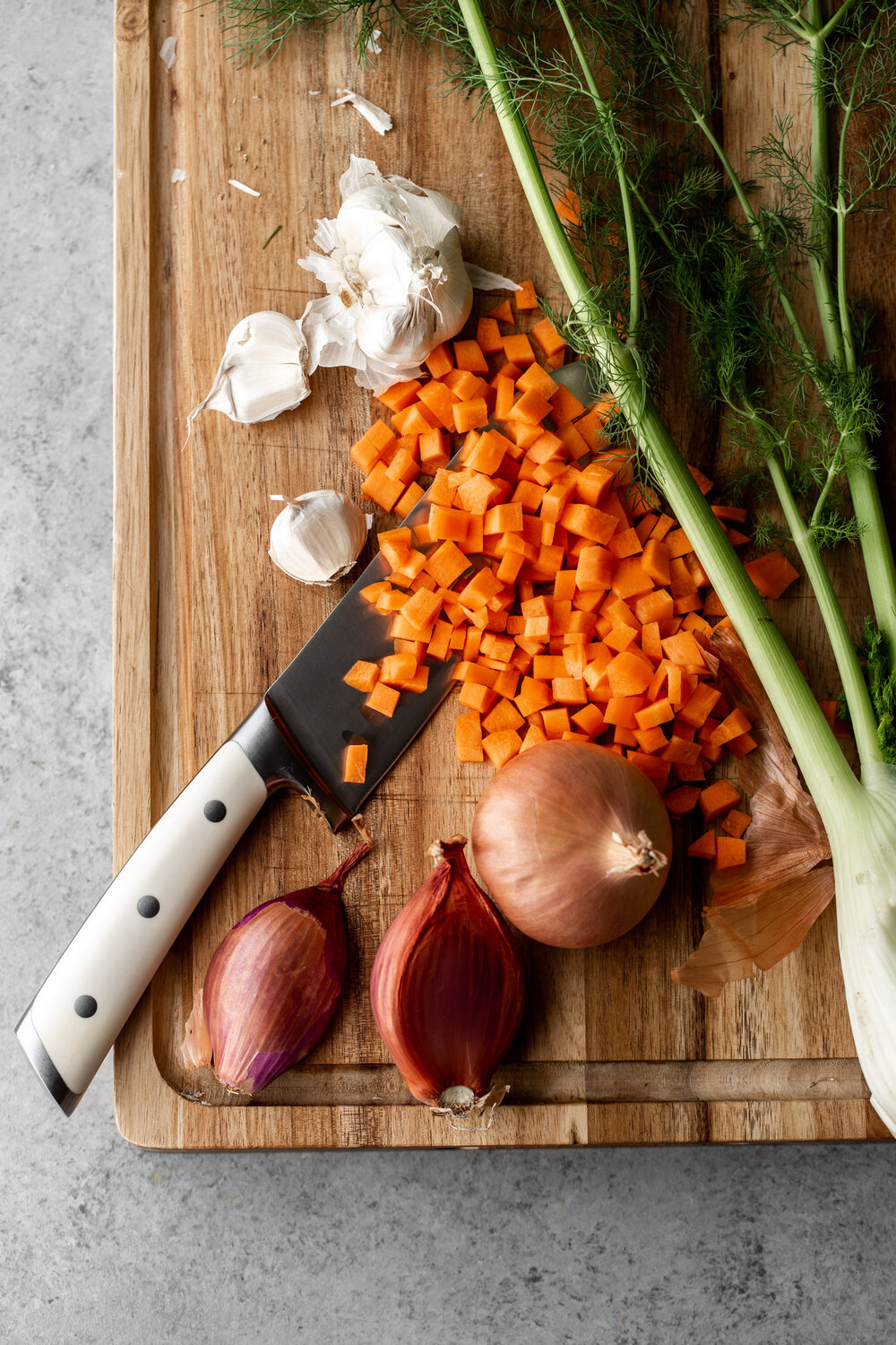 diced carrots on cutting board with shallot and fennel