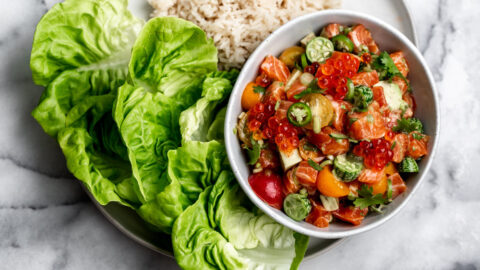 cured diced salmon with cucamelons and tomatoes in a small bowl served with butter lettuce and crispy rice