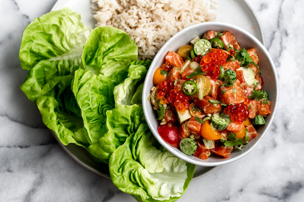 cured diced salmon with cucamelons and tomatoes in a small bowl served with butter lettuce and crispy rice