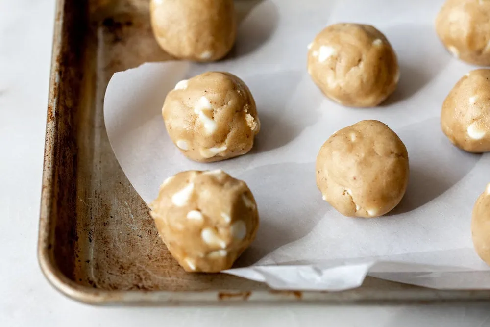 Miso Brown Butter Cookies with White Chocolate Chips balls rolled on baking sheet