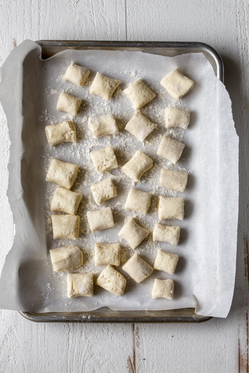 homemade ricotta gnocchi arranged on baking sheet.