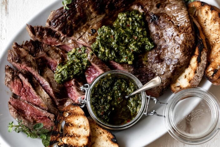 sliced Pan-Seared Flank Steak with Chimichurri Sauce and grilled bread.