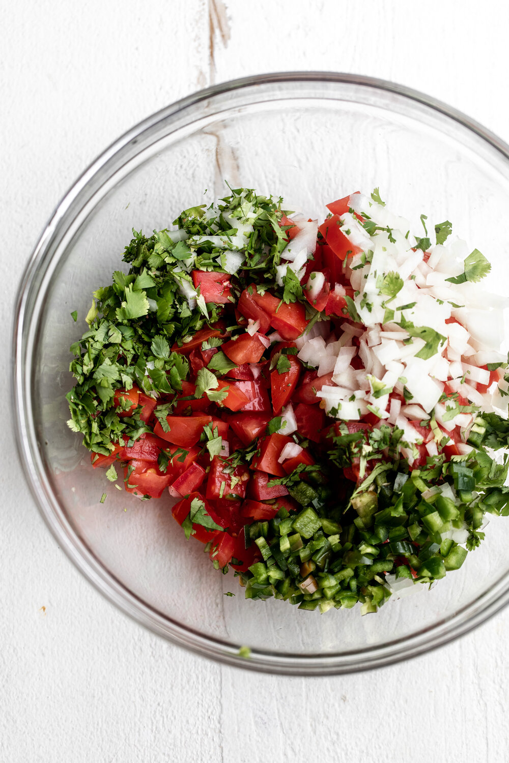 pico de gallo ingredients diced tomatoes onions jalapeño and cilantro with lime in mixing bowl