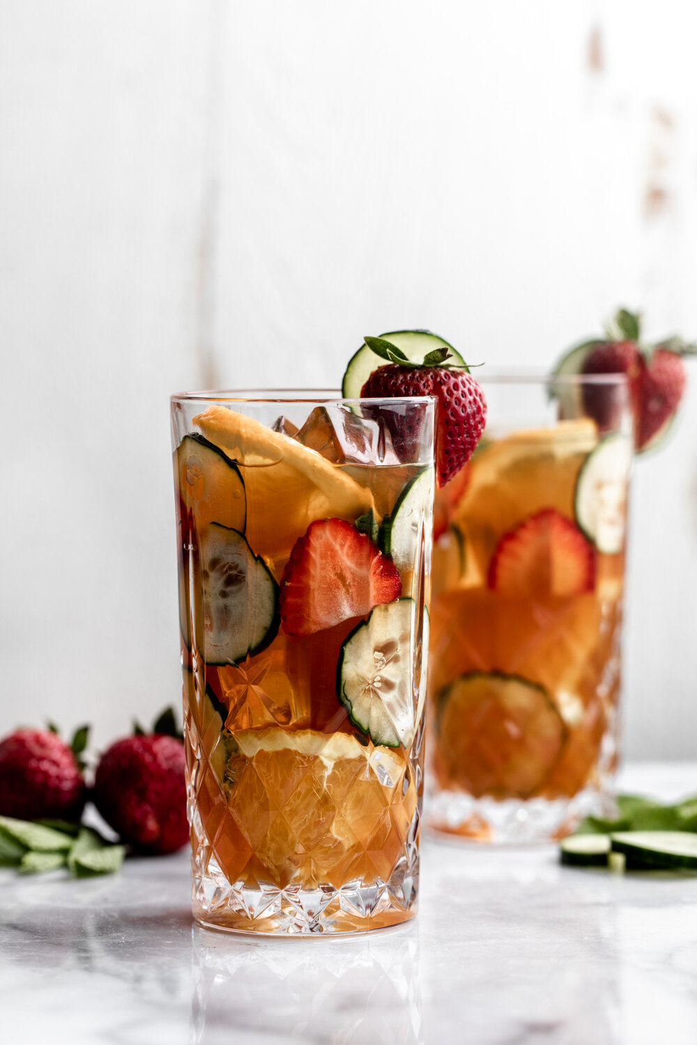 Pimm's Cup with fresh strawberries cucumber and orange slices in a crystal high ball glass