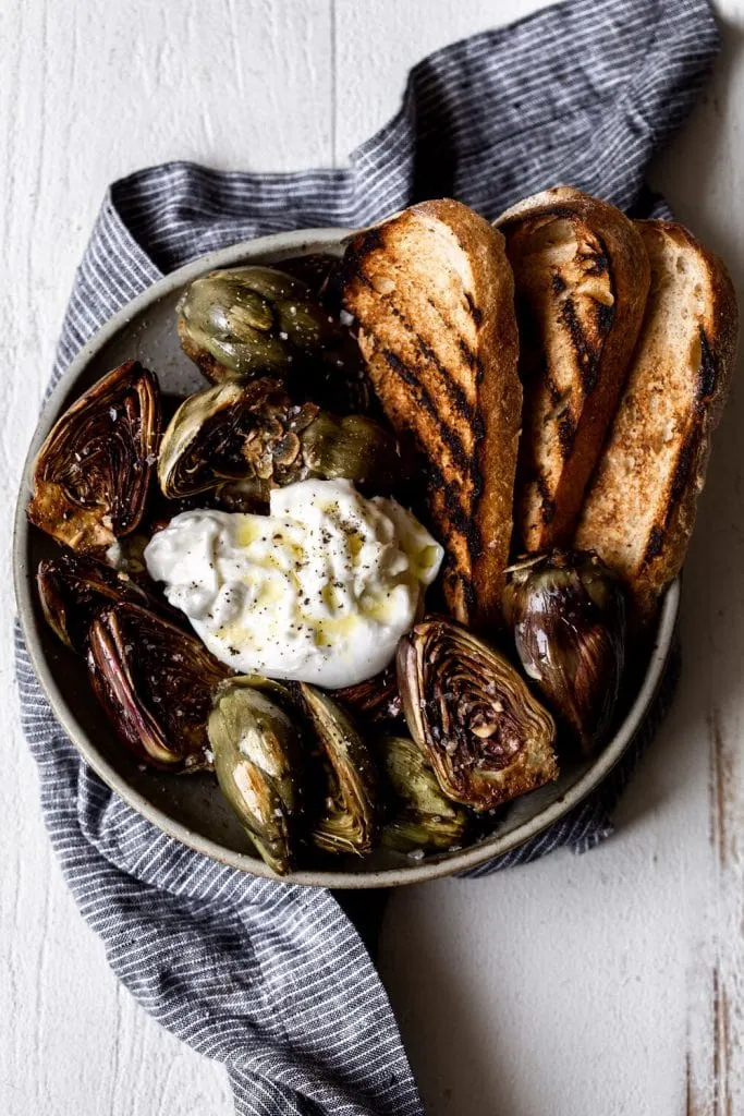 Quick Braised Baby Artichokes with Burrata and grilled bread in bowl.