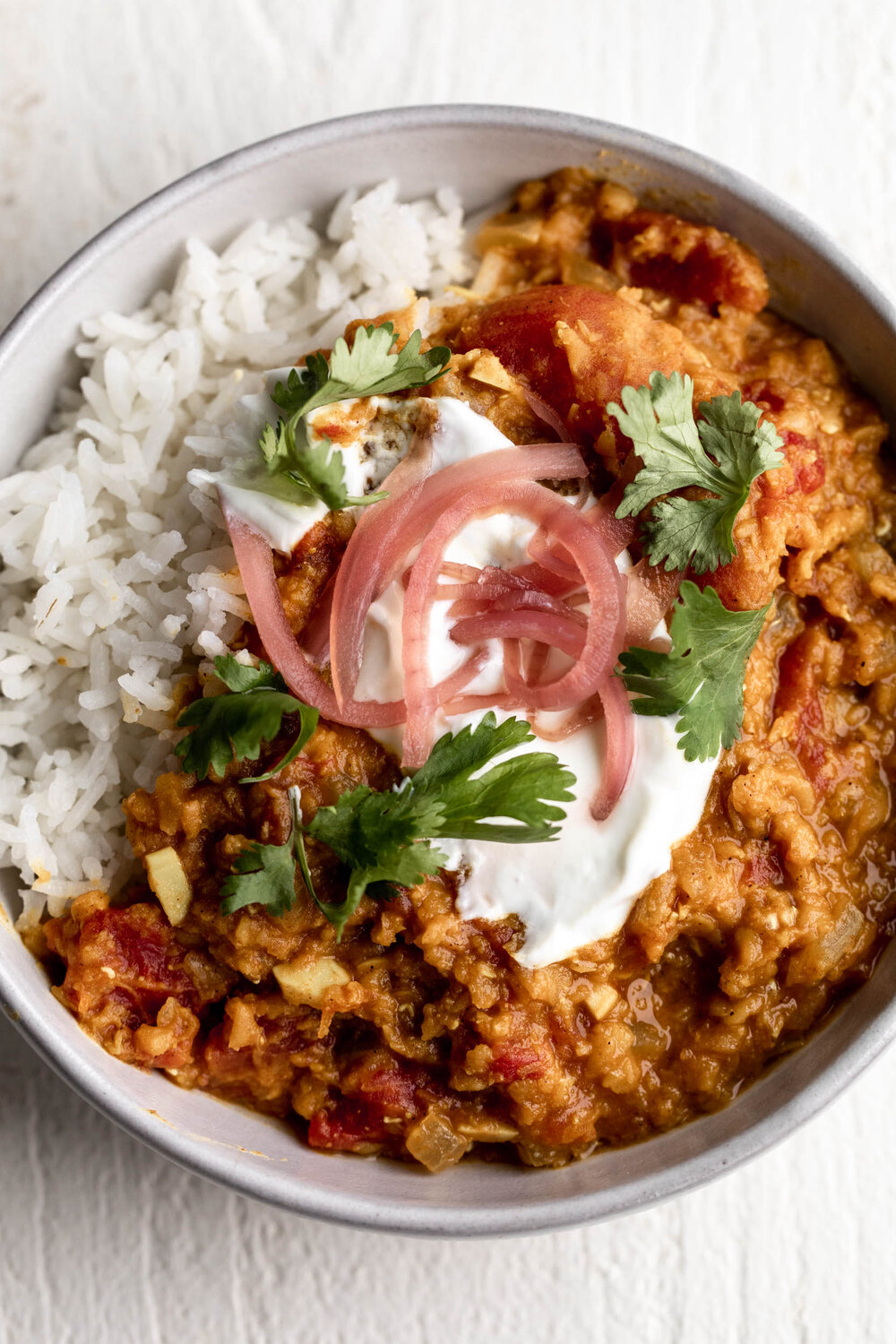 Red Lentil Masoor Dal with rice and topped with yogurt and pickled red onions 