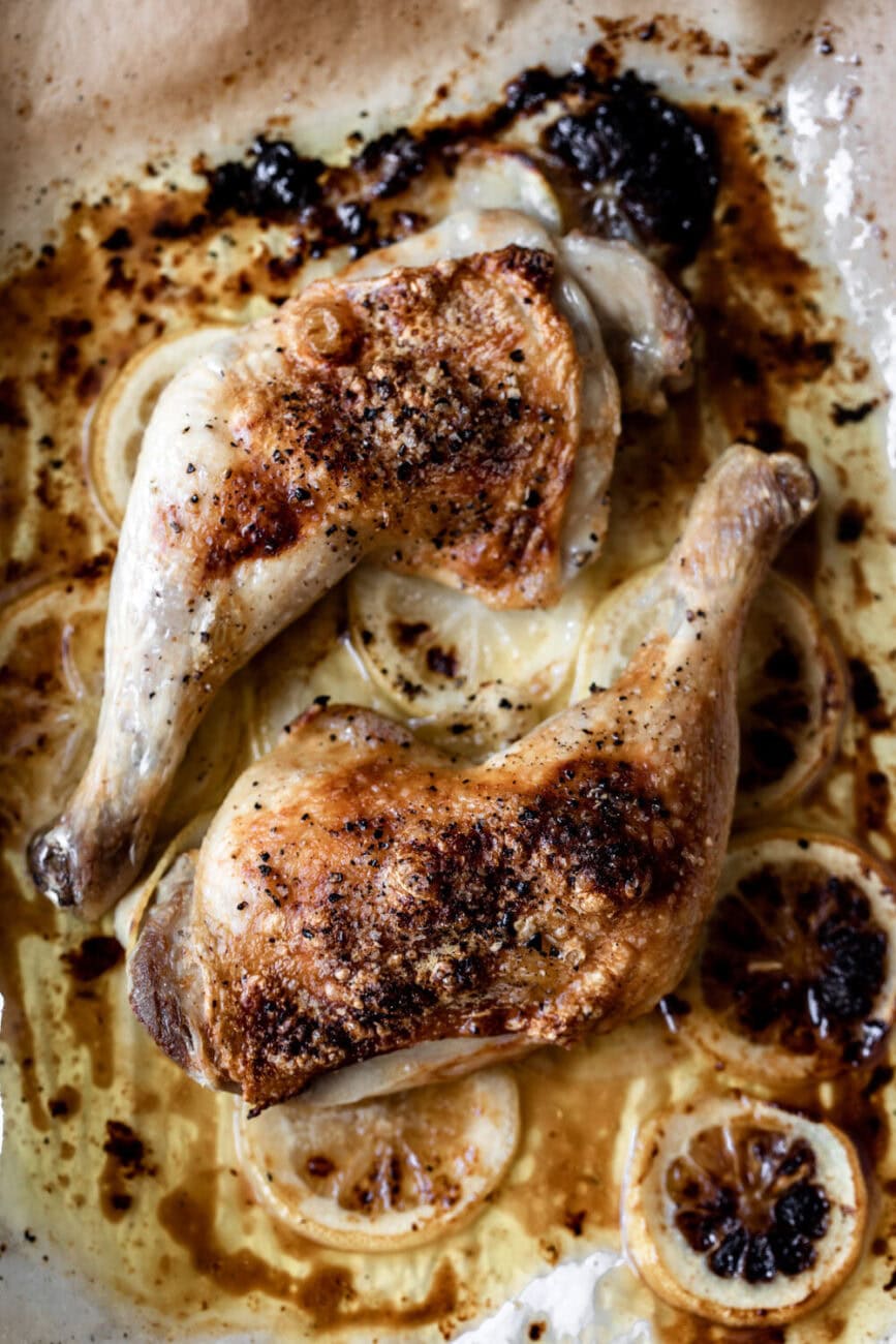 whole roast chicken legs over lemons with crispy skin.
