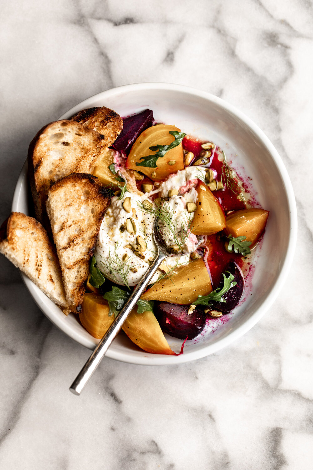 Roasted Beet Salad with Burrata topped with pistachio and fennel fronds with grilled bread