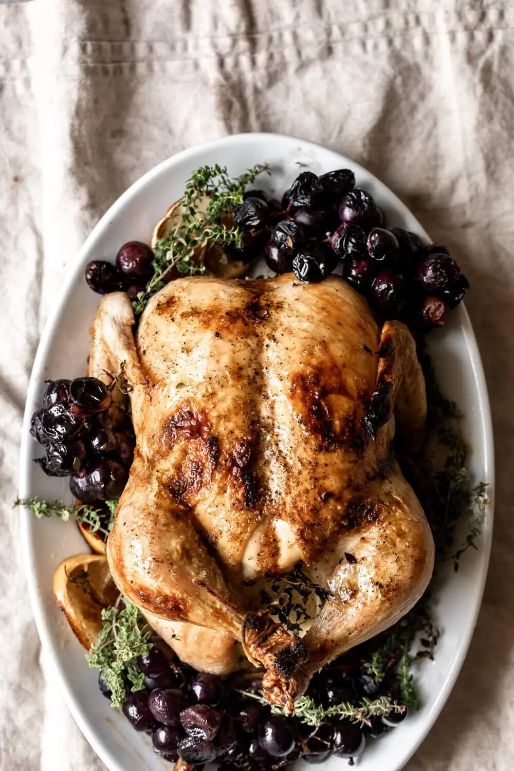 This whole roast chicken is cooked with grapes, thyme and lemon for an easy and impressive seasonal entree. 